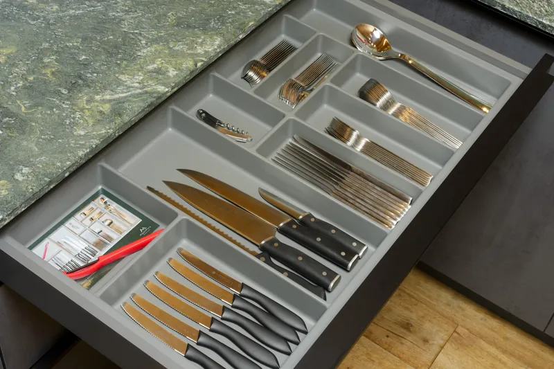 Besteckschublade mit Messern, Gabeln, Löffeln und mehreren Küchenmessern unter der Steinarbeitsplatte